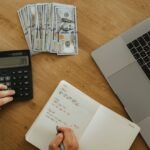 Calculator, notebook, cash and laptop used to work out debt service coverage for an SBA loan
