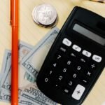 Calculator, pen and cash on a notepad for comparing a business line of credit with a term loan