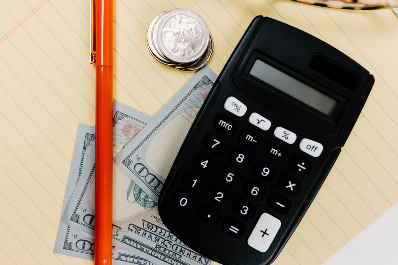 Calculator, pen and cash on a notepad for comparing a business line of credit with a term loan